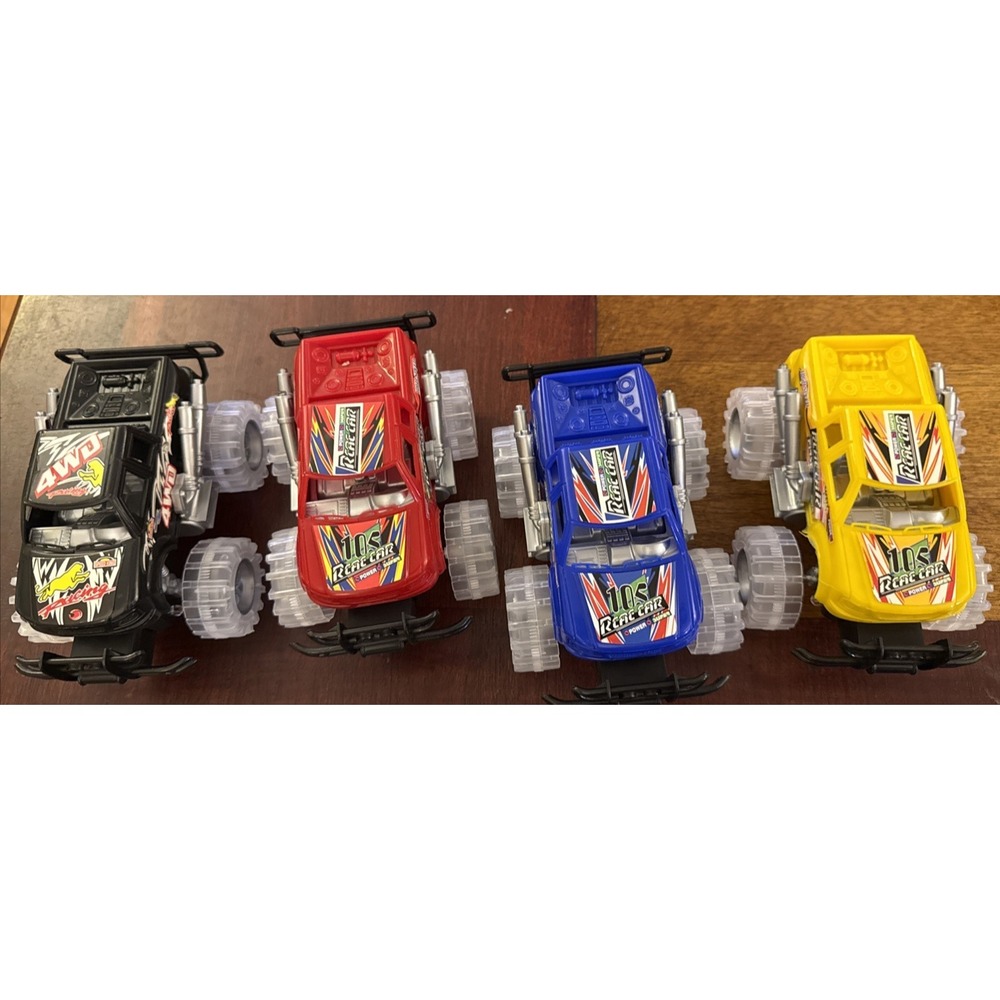 FOUR COLORFUL LARGE 6 INCH LONG "RCAE" MONSTER TRUCKS WITH FLASHING LED LIGHTS